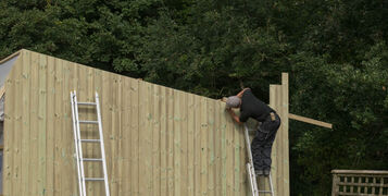 Builders,Cladding,The,Exterior,Of,A,Garden,Shed,With,Tunnel